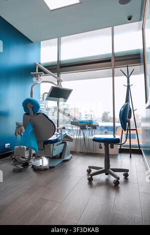 Interno moderno di clinica dentale con sedia di trattamento, attrezzatura dentale e finestra panoramica preparata per l'assistenza al paziente Foto Stock