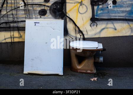 Toilette abbandonata in strada con graffiti sul muro Foto Stock