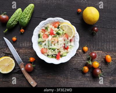 Insalata di couscous con verdure fresche e limone su tavolo di legno Foto Stock