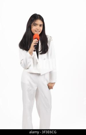 Giovane donna elegante in abito pantalone bianco che tiene un microfono da studio Foto Stock