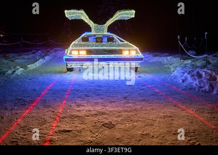 Una scena invernale notturna con una scultura illuminata che assomiglia a una DeLorean DMC-12 con le sue caratteristiche porte a farfalla aperte, posizionata su Foto Stock
