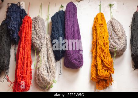 Vivaci strisce di filati di alpaca e lana di pecora tinti naturalmente appesi ad asciugare in una bottega tessile peruviana. Foto Stock