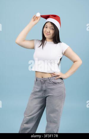 Giovane donna con cappello di Babbo Natale che alza le mani e si gode le festività Foto Stock