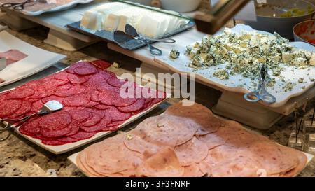 Prima piano di un buffet con salame affettato, prosciutto, formaggio blu e latticini freschi. Assortimento di salumi e formaggi serviti a colazione in un hotel. Foto Stock
