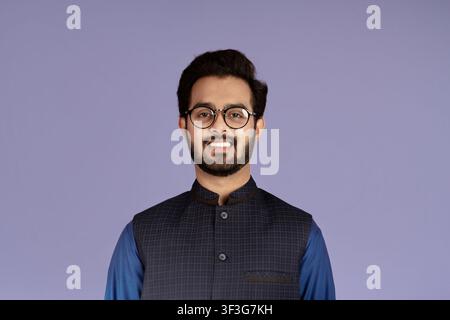 Uomo indiano sorridente che indossa occhiali eleganti su sfondo lilla Foto Stock