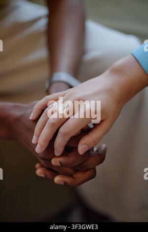 Donna adulta che tiene la mano di un uomo nero in un contesto di assistenza di supporto Foto Stock