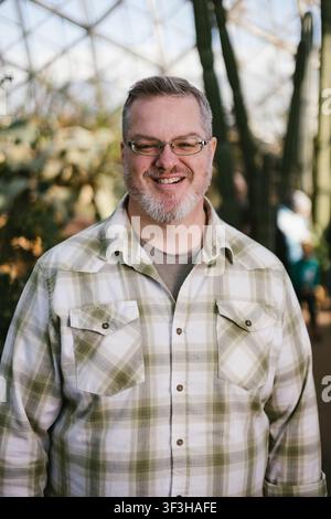 Uomo barbetto felice che si gode una giornata nella serra Foto Stock