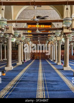 Sala di preghiera con colonne di marmo, lanterne sospese e tappeto blu all'interno della moschea di Al-Azhar, Il Cairo storico, Egitto. Foto Stock