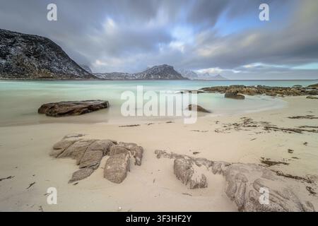 L'ultima luce del sole che risplende sulla costa rocciosa di Vik Strand Beach, Leknes. Tramonto mozzafiato con orizzonte infinito sull'isola di Lofoten, Norvegia, Europa. Mare straordinario Foto Stock