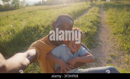 Padre e figlio passano del tempo all'aperto, giocando e ridendo insieme al tramonto. Creano ricordi nella natura. Foto Stock