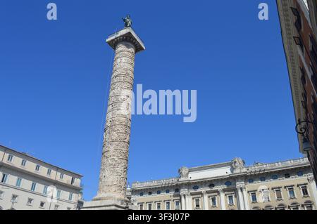 Una magnifica veduta in basso dell'antica Colonna di Marco Aurelio che si erge orgogliosamente contro un cielo azzurro nella Piazza Colonna, a Roma. Foto Stock