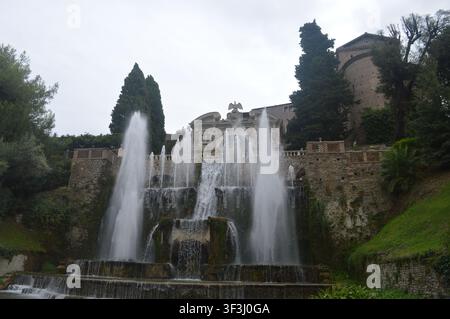 Una magnifica fontana a gradini con potenti getti d'acqua che si riversano lungo i gradini storici in pietra nei lussureggianti giardini della Villa d'Este Foto Stock