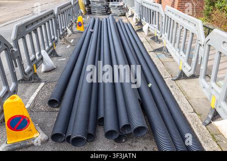 Tubi di plastica neri posati sulla strada per lavori di costruzione Foto Stock