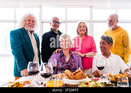 Gruppo di anziani sorridenti di diversi background che godono di una cena dell'amicizia insieme, celebrando la compagnia e uno stile di vita vivace nella terza età aro Foto Stock