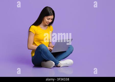 Concetto di lavoro online. Giovane donna coreana sorridente seduto al piano con il laptop Foto Stock