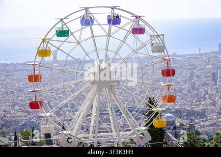 Vista della ruota panoramica colorata del parco divertimenti di Tibidabo che si affaccia sull'ampio paesaggio urbano di Barcellona, Catalogna, Spagna. Foto Stock