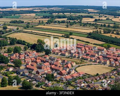 Veduta aerea di Pickering nel North Yorkshire che mostra abitazioni residenziali moderne al confine con campi agricoli ondulati, un mosaico di terreni agricoli e siepi e Foto Stock