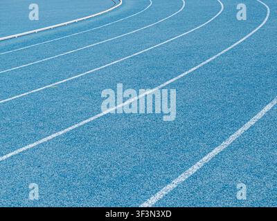 Prima piano di corsie bianche curve su una pista di atletica leggera blu. Foto Stock