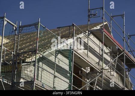 Il moderno edificio residenziale è attualmente in costruzione. Il nuovo edificio è ancora circondato da impalcature. Il tetto è già coperto di t Foto Stock