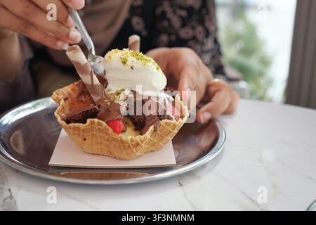 Godendo un dessert in una ciotola di waffle in un caffè Foto Stock