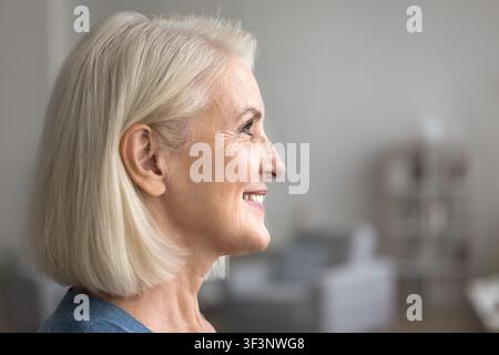 Scatto di profilo di una bella e felice signora anziana che guarda verso l'avanti con un sorriso Foto Stock