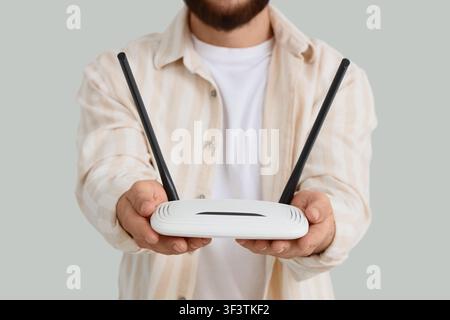 Uomo che tiene un router wireless bianco con due antenne, concetto di connessione Internet e tecnologia di rete, questo dispositivo è essenziale per le comunicazioni moderne Foto Stock