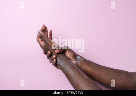 Prima piano delle mani di un uomo di colore che stringono il polso, mostrando dolore e disagio. Concetto di infortunio, sforzo, artrite o sindrome del tunnel carpale con spazio di copia Foto Stock