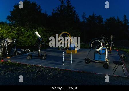 Al crepuscolo, tre telescopi diversi sono pronti per l'uso sui terreni all'aperto dell'Osservatorio Deep Sky Eye su Frotten Road nella Municipalità di Argyle, Nuova Scozia, Canada. Luci fatate lungo il bordo della piattaforma segnano i percorsi tra le stazioni di osservazione. Argyle Municipal, Nuova Scozia, Canada Foto Stock