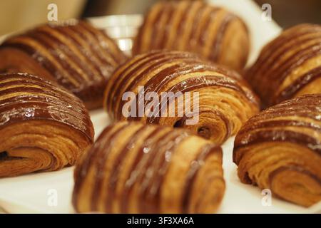 Croissant al cioccolato appena sfornati su un piatto bianco Foto Stock