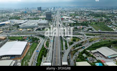 Vista ad angolo alto di un incrocio stradale a più livelli con ponti sopraelevati e flusso di traffico vicino ai settori industriali di Samut Prakan, Thailandia. Foto Stock