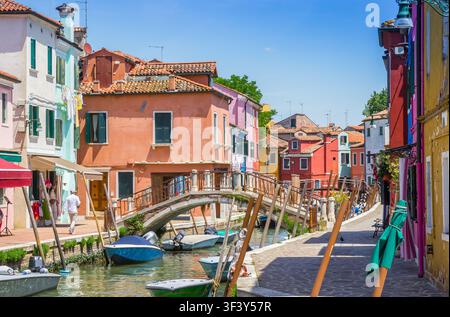 Piccole barche lungo un canale attraversato da un ponte di pietra a Burano, Venezia, Italia Foto Stock