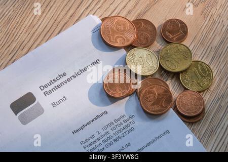 Un primo piano di una intestazione della Cassa pensione federale tedesca su una superficie di legno, su cui giace un piccolo mucchio di monete in centesimi di euro Foto Stock