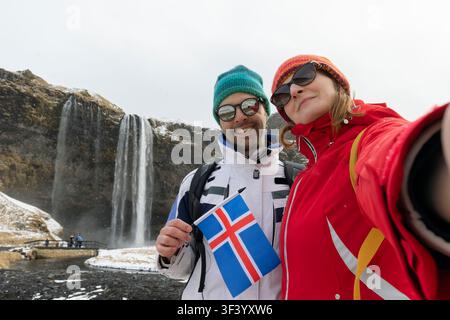 Islanda giovane selfie indossando maglioni islandesi dalla cascata Seljalandsfoss sulla Ring Road nella bellissima natura in Islanda. Donna e uomo mode Foto Stock