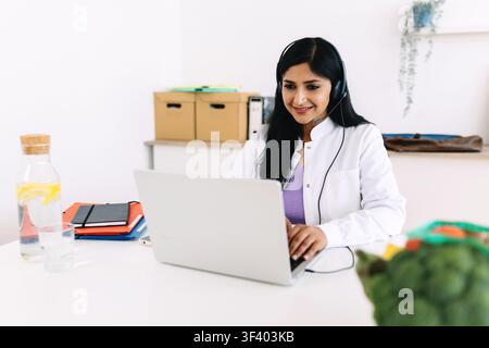 Dietista al lavoro su un laptop durante una sessione di nutrizione virtuale Foto Stock