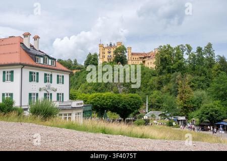 Hohenschwangau, Germania - 07.06.2026: Vista del villaggio di Hohenschwangau con il castello di Hohenschwangau che si erge su una collina boscosa in Baviera. Foto Stock