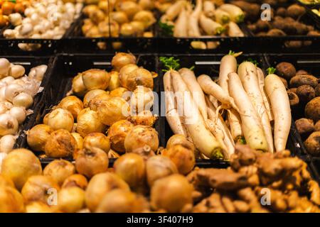 Varietà di ortaggi a radice freschi e cipolle esposti nel reparto frutta e verdura di un supermercato con una selezione di prodotti biologici salutari Foto Stock