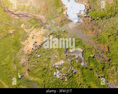 Vista aerea dall'alto di piscine di fango geotermiche, depositi minerali, roccia vulcanica e vegetazione verde che formano motivi naturali in Islanda. Foto Stock