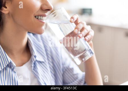 Giovane donna sorridente che tiene un bicchiere d'acqua, primo piano, concetto di benessere Foto Stock