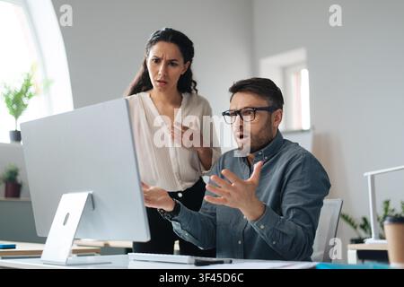 Donna del Medio Oriente preoccupata e collega maschio che guardano lo schermo del computer, ambiente d'ufficio, concetto aziendale Foto Stock