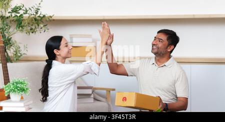 Coppia diversa e felice che si dà il cinque dopo aver ricevuto un pacco di consegna e-commerce a casa Foto Stock