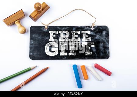 Messaggio regalo gratuito visualizzato su una lavagna con strumenti da ufficio ed elementi creativi Foto Stock
