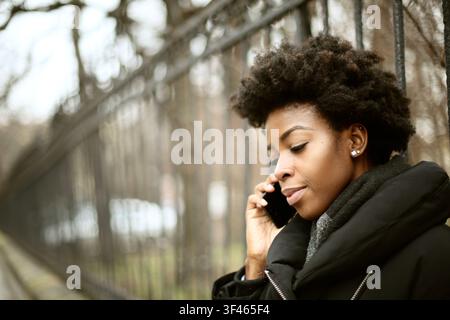 Giovane donna nera che parla al suo smartphone all'aperto Foto Stock