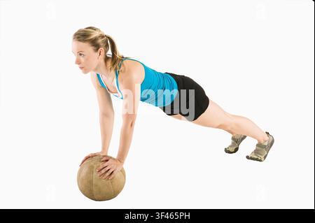 Atleta femminile in equilibrio su una palla da stabilità in posizione da plank Foto Stock