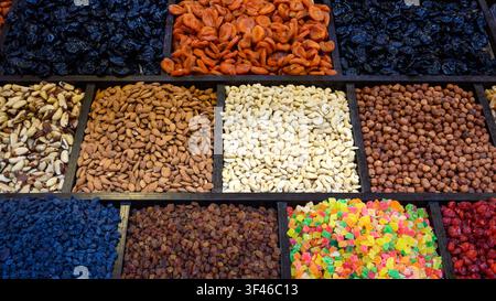 Una fotografia aerea che mostra una varietà colorata di noci e frutta secca disposta in un vassoio di legno compartimentato. La fila superiore contiene Foto Stock