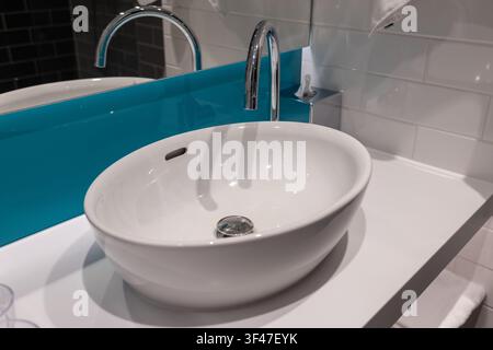 Asciugamani puliti appesi a un lavandino in un bagno moderno con accenti blu e uno specchio Foto Stock