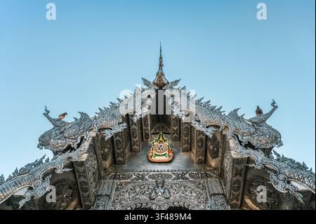 La facciata intricata del Wat Sri Suphan, noto anche come il Tempio d'Argento, a Chiang Mai, Thailandia, che mostra intagli dettagliati in argento contro un cl Foto Stock