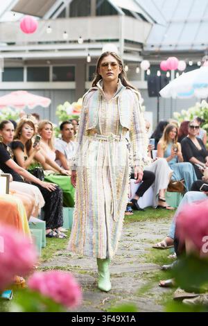 Monaco di Baviera, Germania, 16 luglio 2026. Modella sfilata alla mostra del 20° anniversario di Marcel Ostertag SS27 al Parkhotel Rothof in un trenchcoat di tweed a righe pastello. Foto Stock