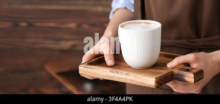Barista che serve una bevanda calda al caffè con latte art in una tazza di ceramica bianca su un vassoio di legno, Ospitalità e servizio caffè, Ospitalità e eccellente caf Foto Stock