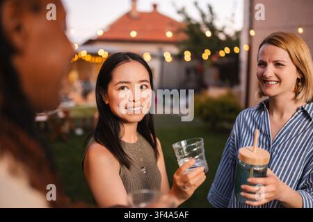 Amici diversi che si divertono insieme a una festa estiva in cortile Foto Stock