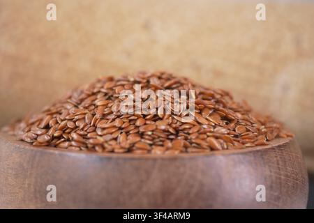 Semi di lino in una ciotola di legno su una superficie rustica Foto Stock